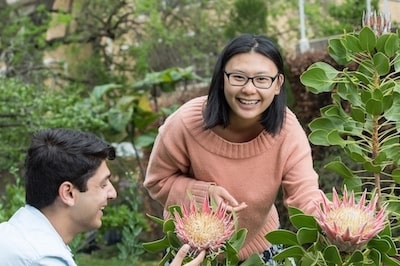 Two students examining a yellow and pink flower in the rooftop garden at Burnley campus
