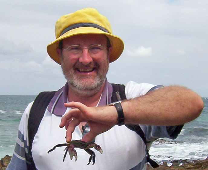 roger cousens is smiling and holds a small crab by the claw