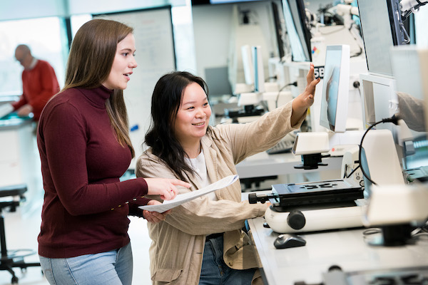 A supervisor and graduate researcher examining the screen of a powerful microscope