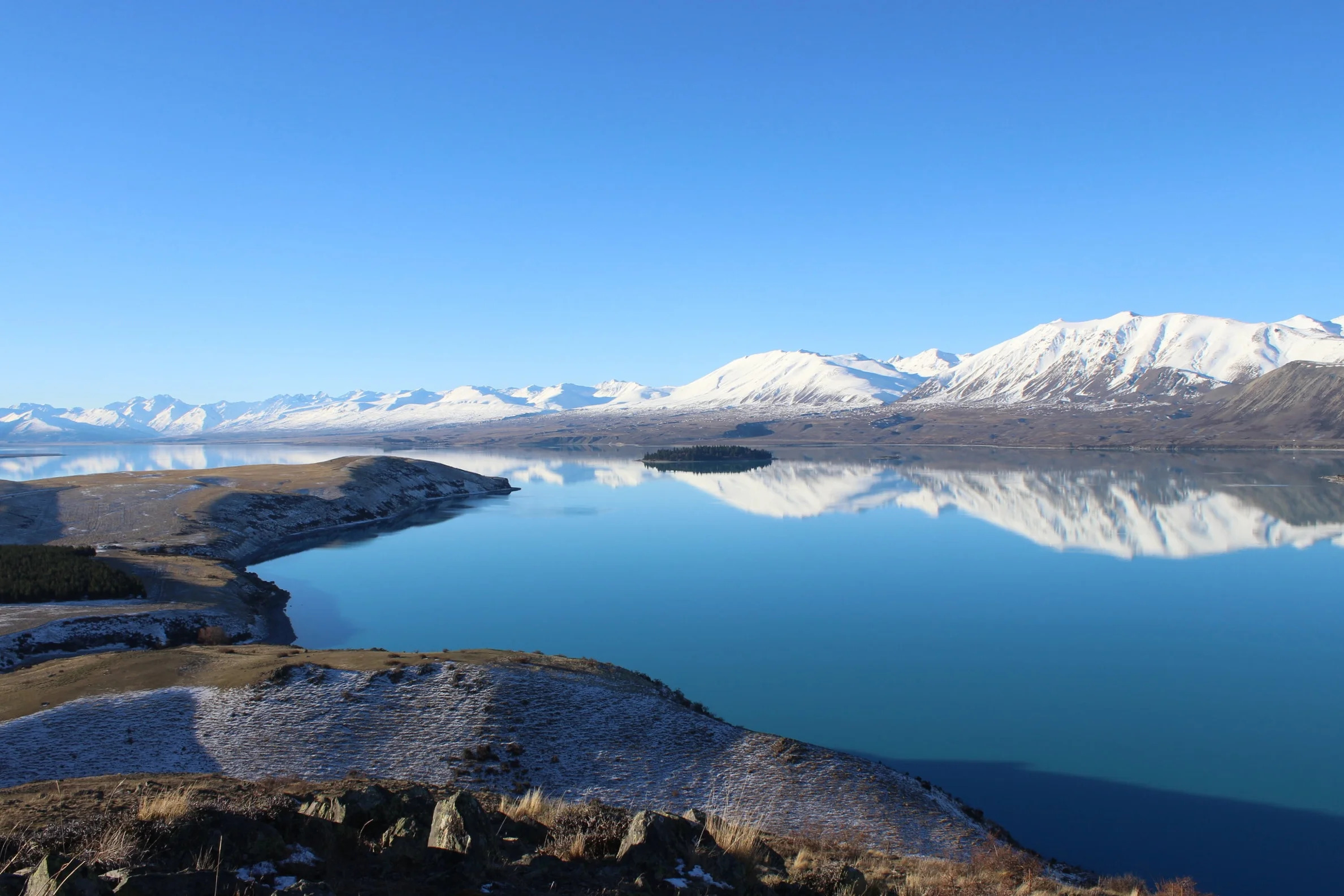 Snow covered mountains next to a lake